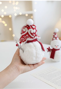 Detail of plush Christmas snowmen with red knitted hats and festive scarves on desk