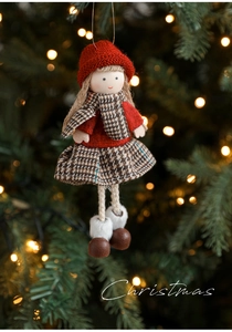 Detail of plush Christmas girl doll ornament with red knit hat on a festive lit tree
