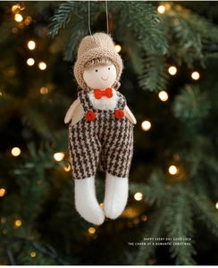 Close-up of a Christmas plush doll ornament with knitted hat on a festive tree