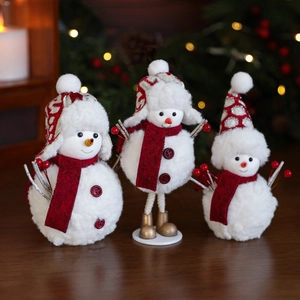 Three plush Christmas snowmen with red knit hats and scarves on dark wood table
