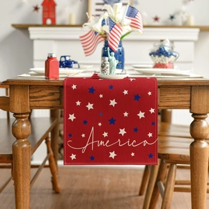 Detail of red linen Fourth of July table runner with white America script and blue stars