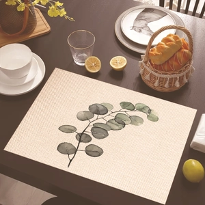 Detail of a rectangular tropical leaf placemat on a wooden table with ceramic tableware