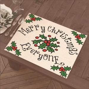 Close-up of Christmas placemat with Merry Christmas text and holly berries on wood table