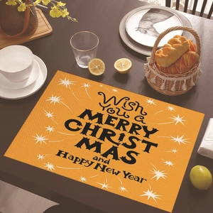 Orange Merry Christmas table mat with star pattern and festive lettering on wooden table