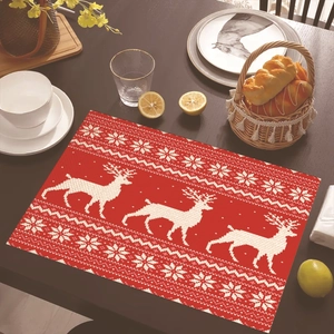 Red Christmas placemat with white elk and snowflake patterns on a rustic wooden table