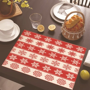 Close-up of woven Christmas placemat with red stripes and snowflakes on wood table