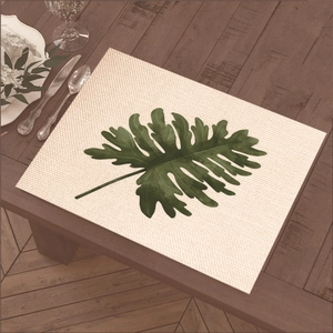Rectangular beige placemat with green tropical leaf print on a wooden dining table