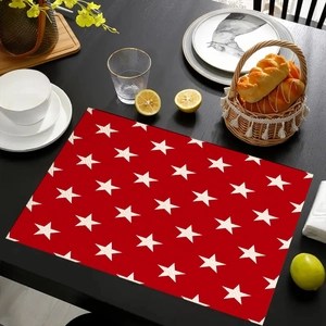 Detail of red placemat with white star pattern on a black dining table with dinnerware