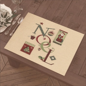 Beige Christmas NOEL placemat with festive hand-drawn illustrations on a wooden table