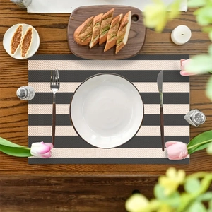 Striped linen textured placemat in black and beige on a wooden table with tableware