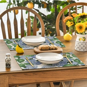 Close-up of rectangle placemat with blue hydrangea and green leaves on wooden table