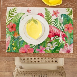 Tropical placemat featuring flamingo and green leaf prints on a rustic wooden table