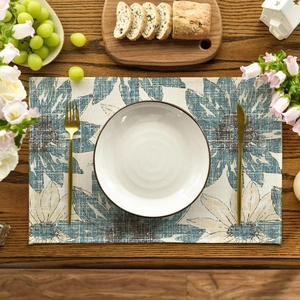 Detail of sunflower pattern placemat with white plate and golden cutlery on wooden table