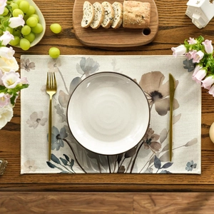 Linen placemat with floral pattern on dark wood table with cutlery and fruit