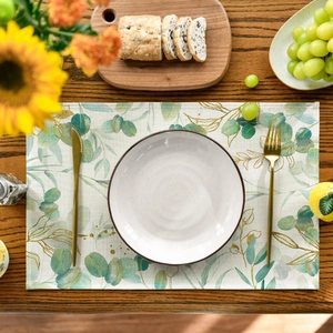 Detail of eucalyptus leaf print placemat with gold veins on a wooden table setting