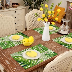 Macro shot of tropical monstera leaf placemats on a rustic wooden dining table