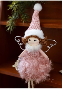 Detail of plush Christmas angel doll with pink knit hat and soft wings on wood shelf