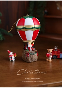Detailed Christmas resin ornament featuring Santa hot air balloon and snowmen on wooden table