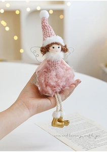 Detail of pink plush angel ornament with knitted hat and gold boots held in hand