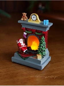 Close-up of a lit miniature Christmas fireplace with Santa and glowing LED warmth