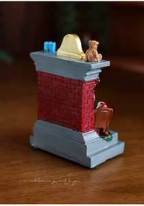 Macro detail of miniature resin fireplace ornament with small bear and gift box decor