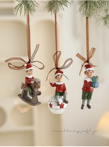 Detailed close-up of three vintage resin Christmas elf ornaments hanging on pine branches