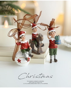 Three resin Christmas elf ornaments with gift and rocking horse on white book setting
