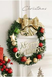 Détail d'une couronne de Noël avec cloches dorées, nœuds et boules sur un mur blanc