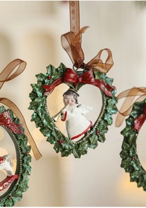 Detail of heart-shaped holly wreath ornament with a small angel and red bow decoration