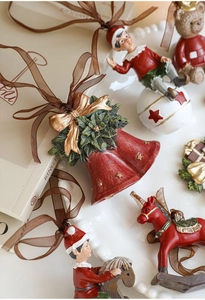 Detail of vintage hand-painted resin Christmas bells and ornaments on a white plate