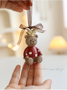 Detail of resin bear ornament with gold crown and red plaid sweater for Christmas trees