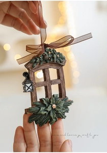 Detail of resin window ornament with green pine needles and a silk ribbon for hanging