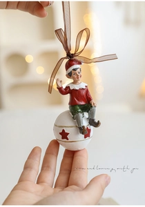 Close-up of a resin Christmas elf ornament on a white ball with warm bokeh lights