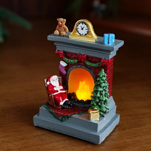 Christmas glowing fireplace ornament with Santa sitting in a chair and mini LED lit tree
