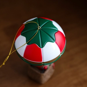 Christmas hot air balloon ornament with red white and green stripes on wooden background