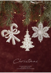 Detail of white and gold Christmas ornaments hanging on a festive green pine branch