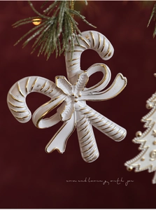 Detail of matte white and gold candy cane Christmas ornament with holly leaves and berries