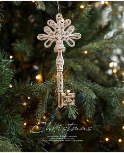 Macro detail of vintage white and gold Christmas key ornament hanging on a festive tree