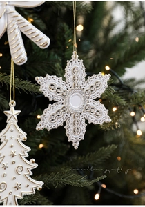 Close-up of matte white snowflake and candy cane ornaments with gold relief details