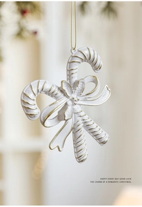 Close-up of matte white and gold crossed candy cane ornament with a bow for Christmas tree