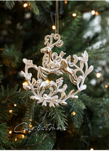 Detail of a matte white and gold baroque reindeer ornament hanging on a Christmas tree