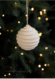 Close-up of beige woven cotton rope Christmas ball ornament with a warm holiday glow