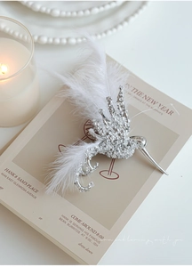 Detailed view of hummingbird ornament featuring silver metal base and white feathers