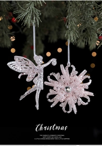 Macro detail of pink glitter Christmas fairy and snowflake ornaments on a pine branch