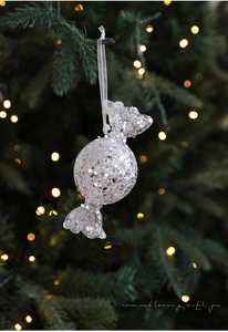 Sparkling candy-shaped Christmas ornament with silver sequins on a festive tree