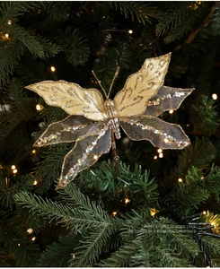 Close-up of golden mesh butterfly clip with sequins on a lit Christmas tree