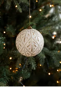Detail von cremeweißem Weihnachtsschmuck mit Goldblatt-Textur an leuchtendem Baum