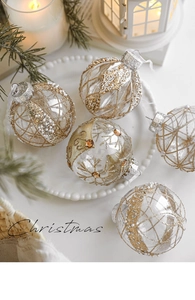 Detail of 8cm clear Christmas balls with gold glitter and pearls in a cozy winter setting