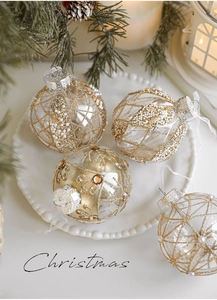 Detail of 8cm transparent Christmas balls with gold glitter patterns and pearls on a plate