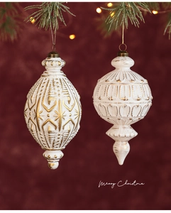 Detail von vintage mattweißen Weihnachtskugeln mit Goldmustern an einem Tannenzweig